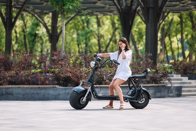 Mujer hermosa joven y un transporte ecológico scooter eléctrico