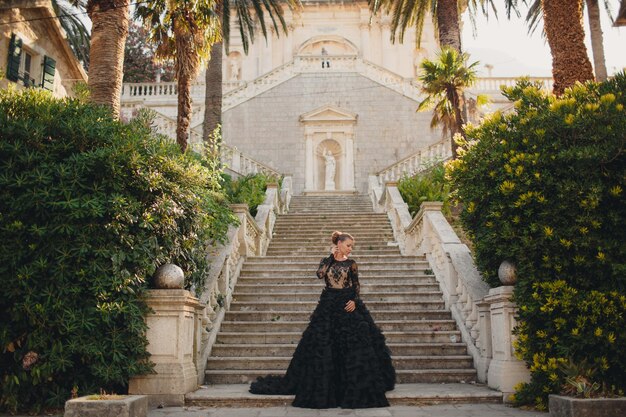 mujer hermosa de moda en vestido de lujo negro al aire libre