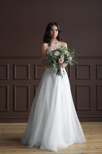 Mujer hermosa novia en vestido de novia elegante con ramo de flores