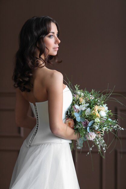 Mujer hermosa novia en vestido de novia elegante con ramo de flores