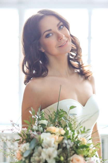 Mujer hermosa novia en vestido de novia elegante con ramo de flores