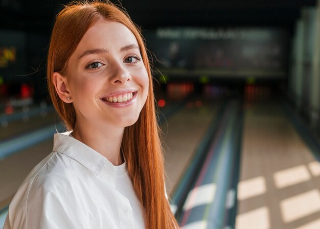 Mujer hermosa pelirroja en un club de bolos