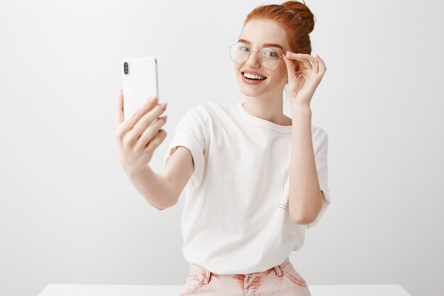 Mujer hermosa pelirroja tomando selfie con gafas