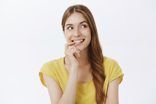 Mujer hermosa pensativa sonriendo curiosa, mirando en la esquina superior derecha