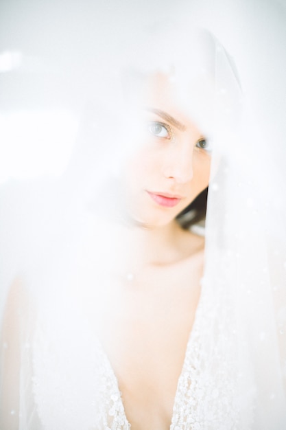 Mujer hermosa que se coloca y que mira en sitio con blanco en el vestido blanco largo.