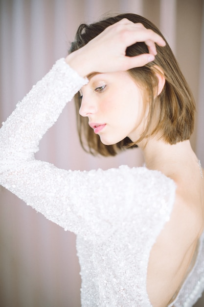 Foto gratuita mujer hermosa que se coloca y que piensa en sitio con la perla en la camisa blanca.