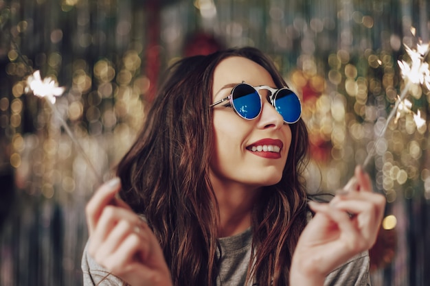 Mujer hermosa que sostiene bengalas en manos