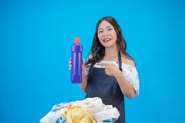 Mujer hermosa que sostiene el detergente para ropa preparado en azul