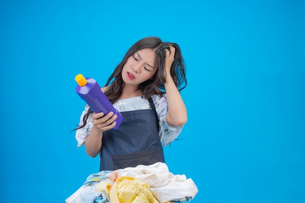 Mujer hermosa que sostiene el detergente para ropa preparado en azul