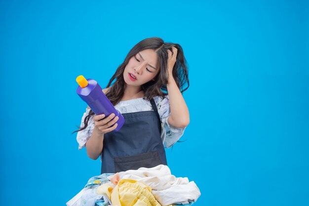 Mujer hermosa que sostiene el detergente para ropa preparado en azul