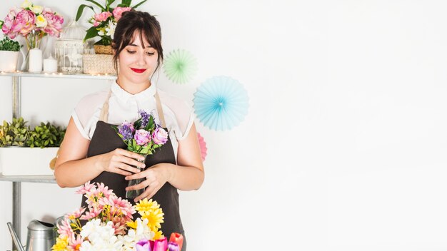 Mujer hermosa que sostiene el florero fresco en tienda floral