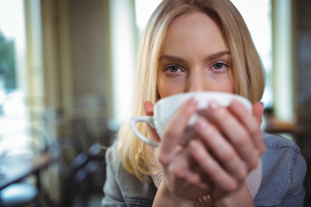 Mujer hermosa que tiene una taza de café en la cafetería ©