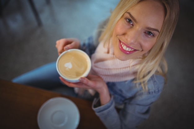 Mujer hermosa que tiene una taza de café en la cafetería ©