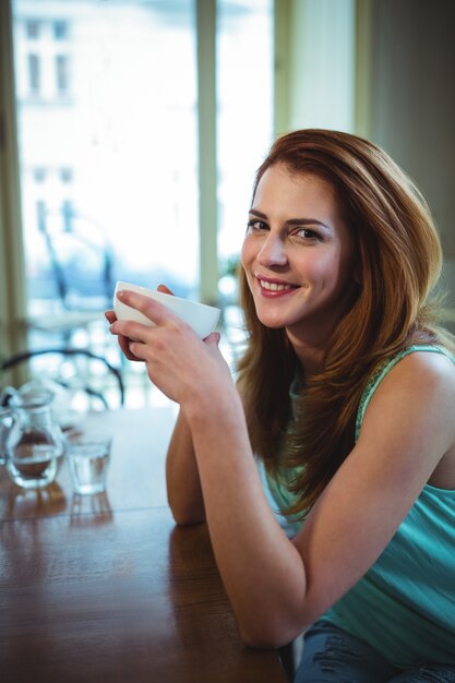 Mujer hermosa que tiene una taza de café en la cafetería ©