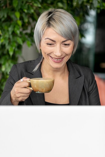 Mujer hermosa sonriente que goza del café