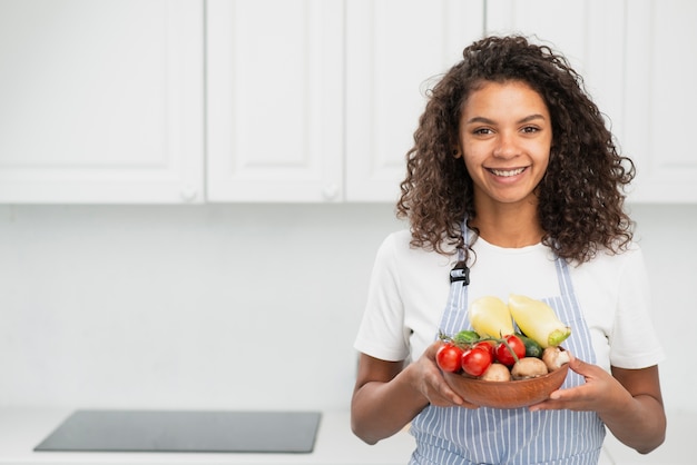 Mujer hermosa sonriente que sostiene verduras