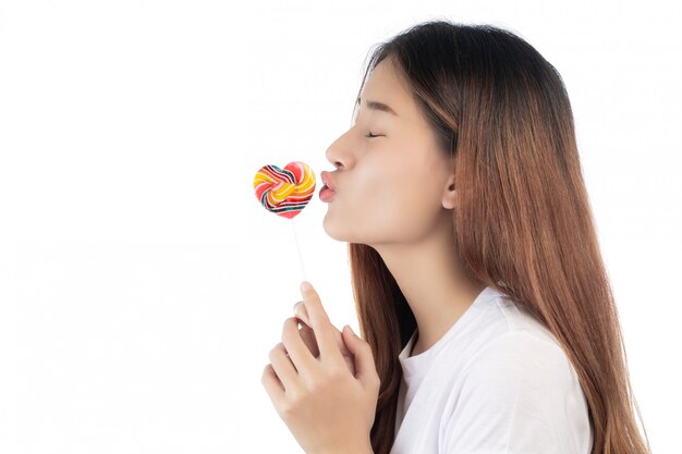 Mujer hermosa con una sonrisa feliz que celebra un caramelo de la mano, aislado en el fondo blanco.