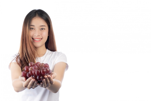 Mujer hermosa con una sonrisa feliz que celebra una uva de la mano, aislada en el fondo blanco.