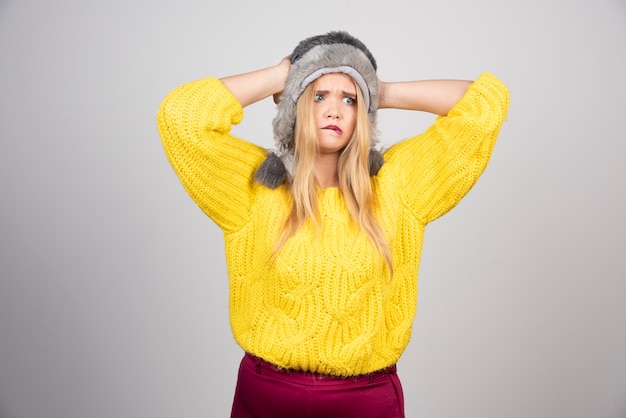 Mujer hermosa en suéter amarillo sosteniendo su cabeza.