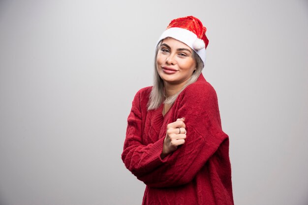 Mujer hermosa en suéter rojo sonriendo a la cámara.