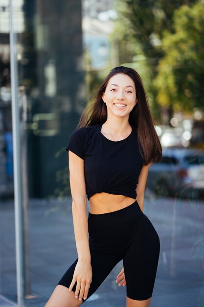 Mujer hermosa, verano en la ciudad, entrenamiento físico en la calle, ropa deportiva.