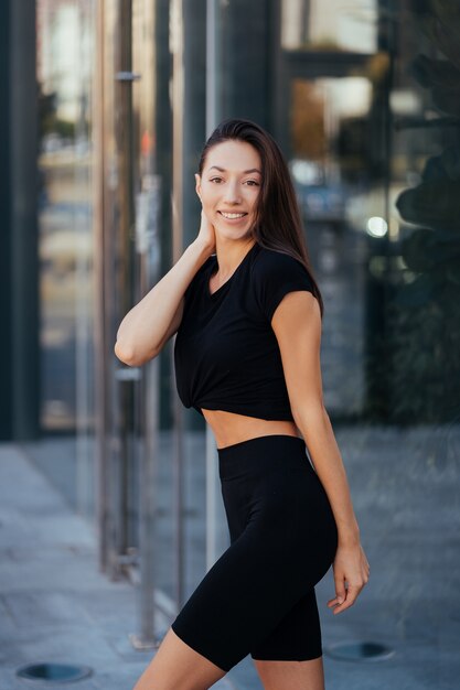 Mujer hermosa, verano en la ciudad, entrenamiento físico en la calle, ropa deportiva.