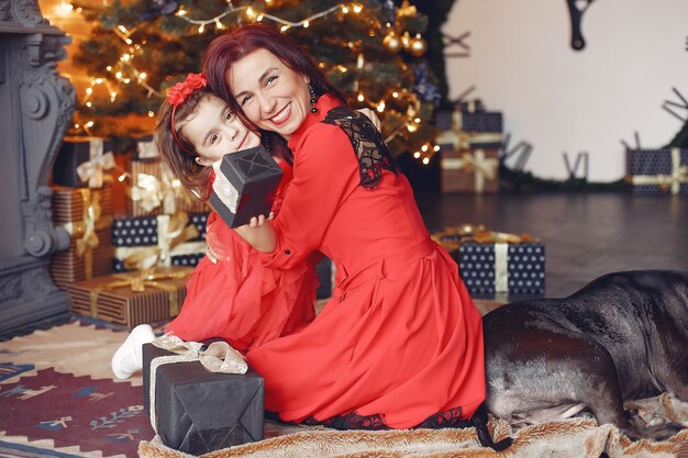 Mujer hermosa en un vestido rojo. Familia en casa. Madre con hija. Personas con perro.