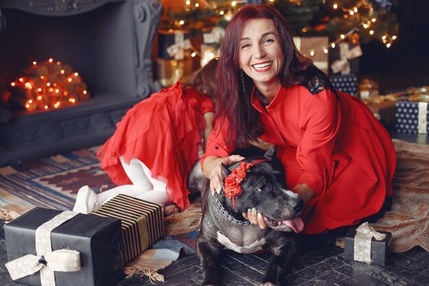 Mujer hermosa en un vestido rojo. Familia en casa. Madre con hija. Personas con perro.