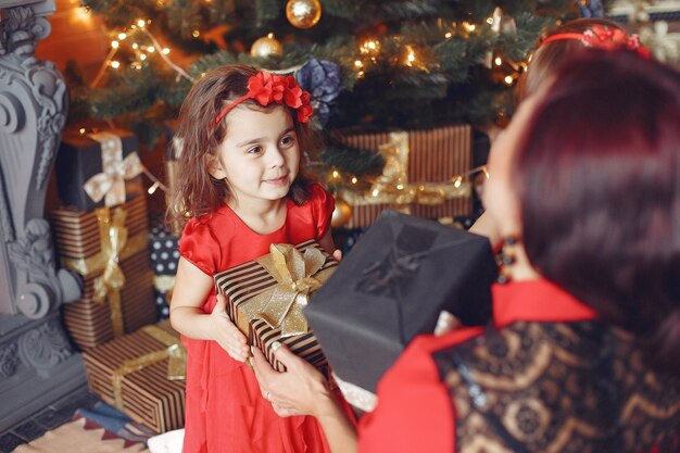 Mujer hermosa en un vestido rojo. Familia en casa. Madre con hija.