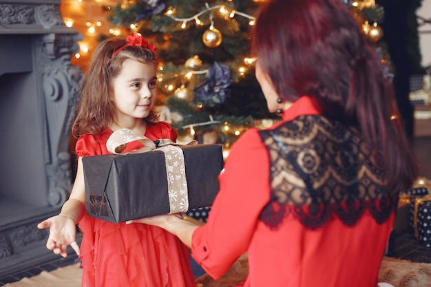 Mujer hermosa en un vestido rojo. Familia en casa. Madre con hija.