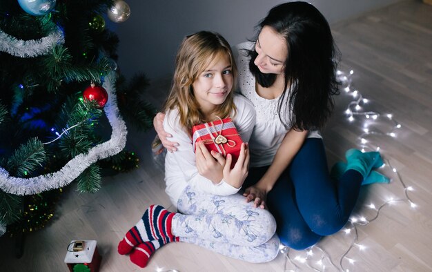 Mujer con la hija en el árbol de navidad