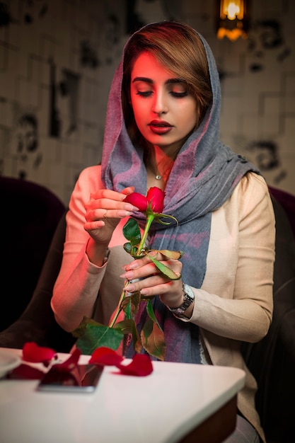 Mujer en hijab con una rosa en restaurante