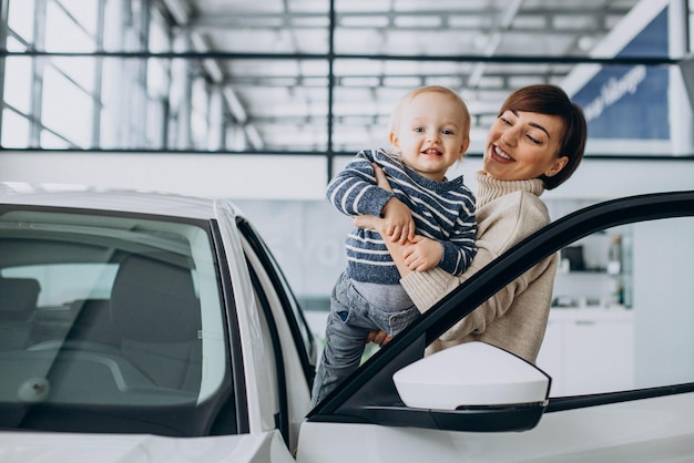 Foto gratuita mujer con hijo eligiendo un auto en un salón de autos