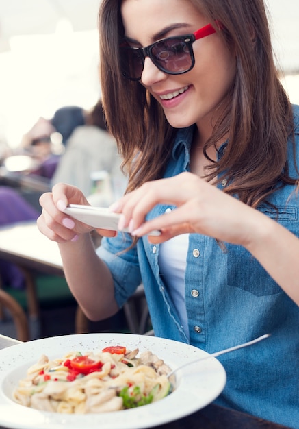 Mujer hipster tomando una foto de comida italiana