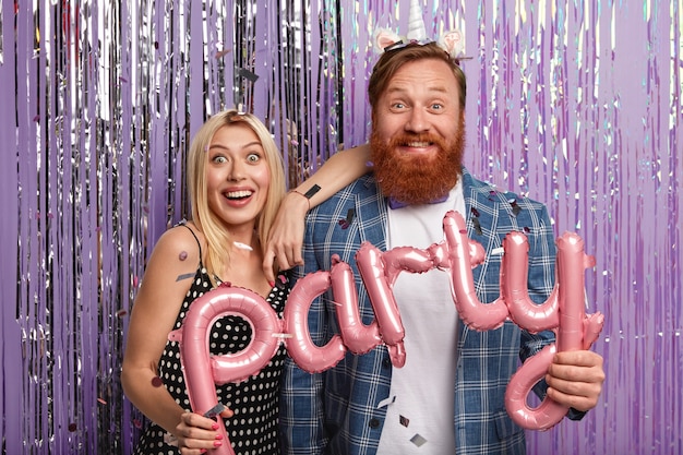 La mujer y el hombre alegre y despreocupado sostienen globos que significan fiesta, vamos evento festivo