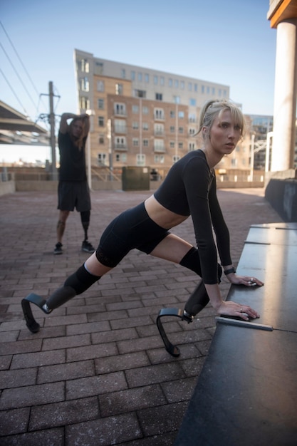 Foto gratuita mujer y hombre con discapacidad en la pierna haciendo ejercicio en la ciudad