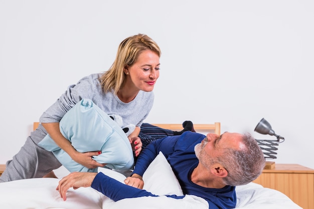 Foto gratuita mujer y hombre envejecidos que se divierten con las almohadas y que mienten en cama