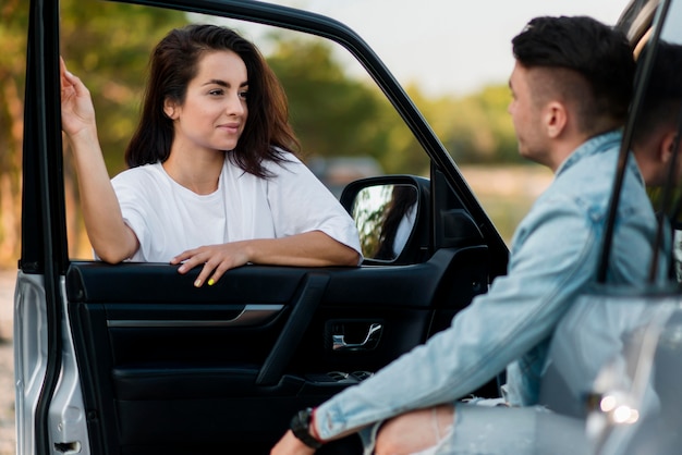 Foto gratuita mujer y hombre hablando y sosteniendo la puerta de un coche