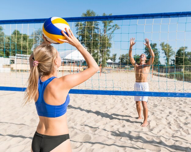 Mujer y hombre jugando voleibol de playa juntos
