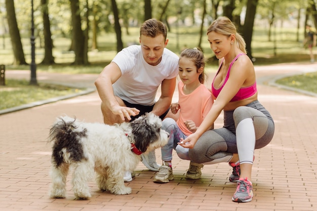 Mujer, hombre y niña van a pasear con su perro en el parque