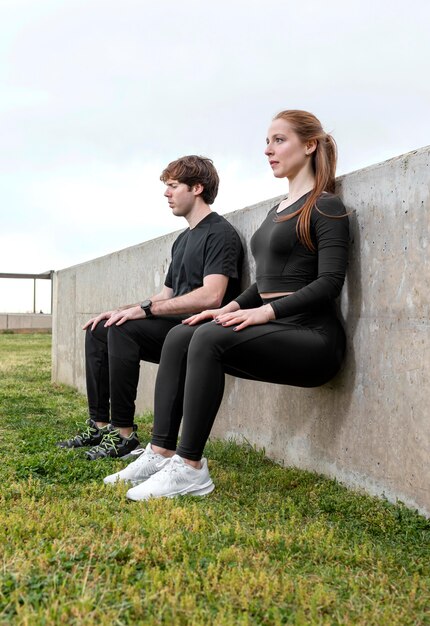 Mujer y hombre en ropa deportiva haciendo ejercicio al aire libre
