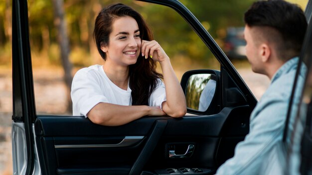 Mujer y hombre sonriendo y sosteniendo la puerta de un coche