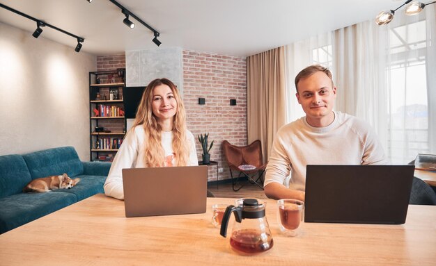 Mujer y hombre sonrientes que trabajan en una computadora portátil en un hogar moderno