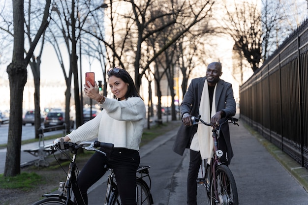 Mujer y hombre tomando selfie y andando en bicicleta en la ciudad de francia