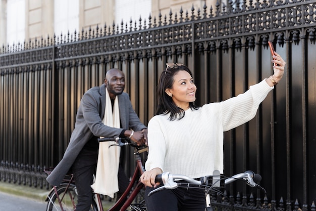 Mujer y hombre tomando selfie y andando en bicicleta en la ciudad de francia