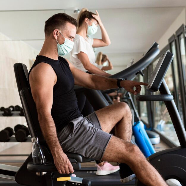 Mujer y hombre trabajando en el gimnasio con máscaras médicas