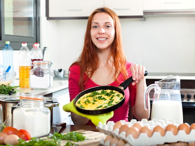 Mujer con huevos revueltos en la sartén en casa