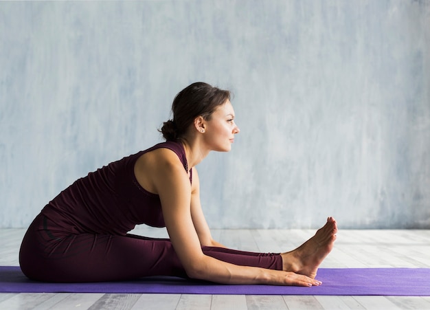 Foto gratuita mujer inclinada hacia adelante mientras practica yoga