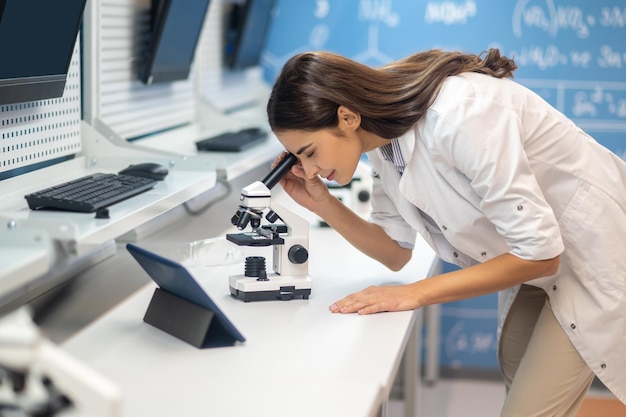 mujer, se inclinar, encima, microscopio, de lado, a, cámara