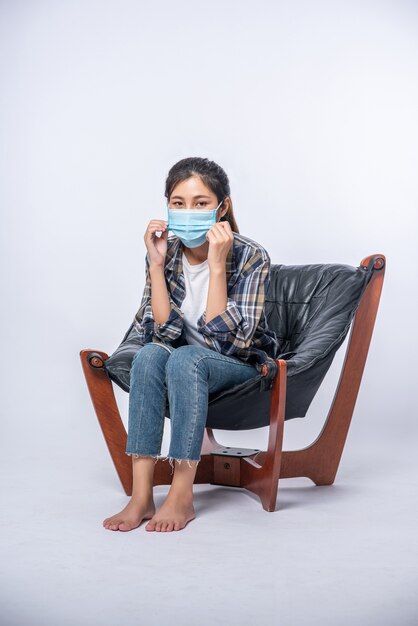 Una mujer incómoda sentada en una silla y con una máscara